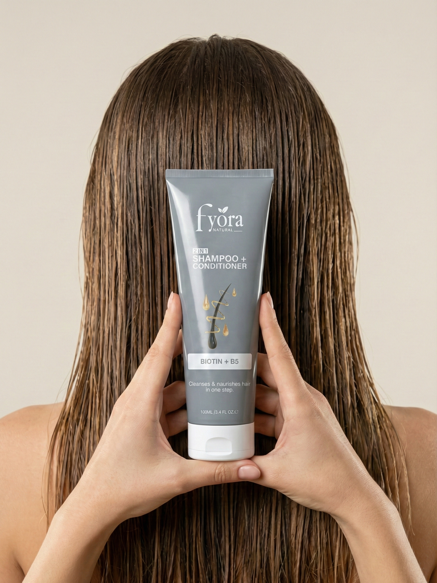 Person holding a bottle of fyora shampoo and conditioner with long hair.